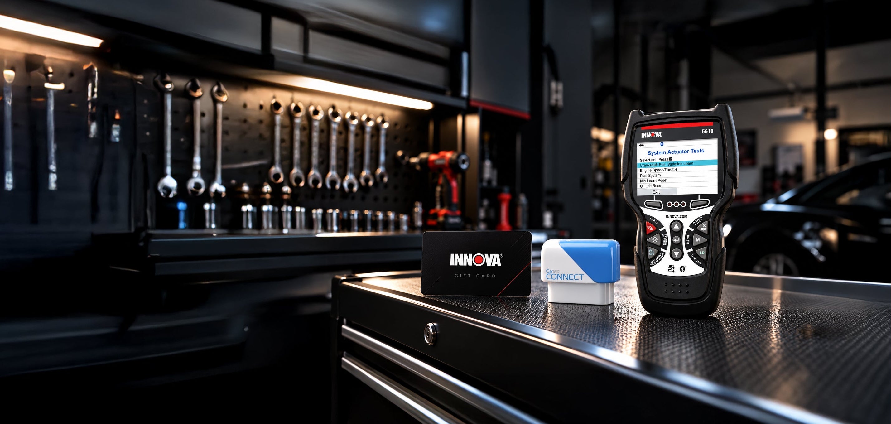 The Innova 5610 beside a CarMD Connect and an Innova gift card, on a tool chest in a workshop