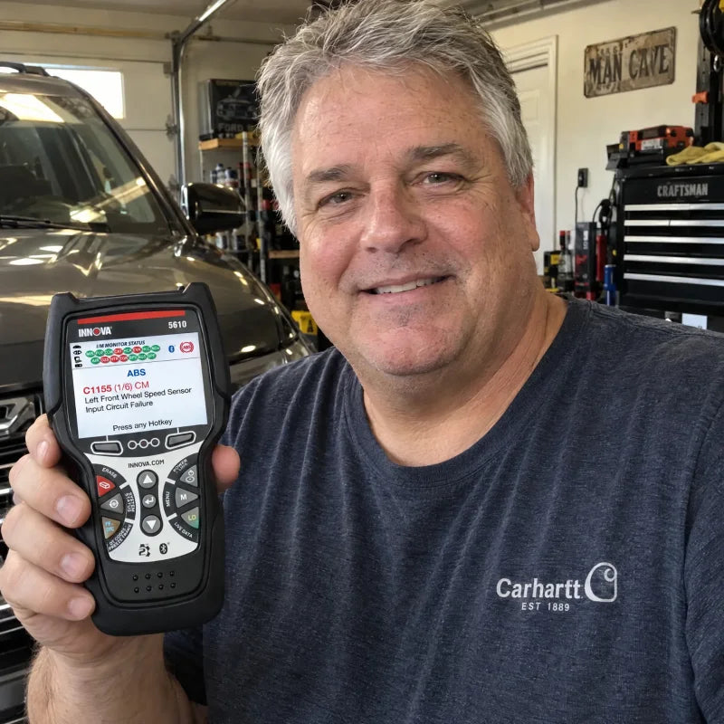 A man in his garage holding up the Innova 5610, an ABS fault on its screen